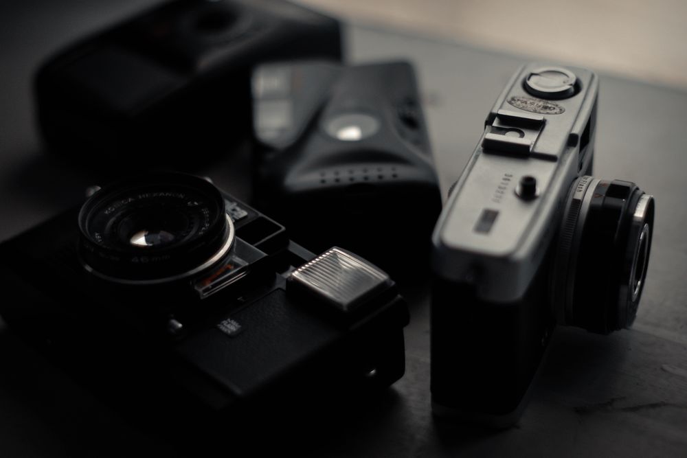 Three vintage film cameras on a dark surface