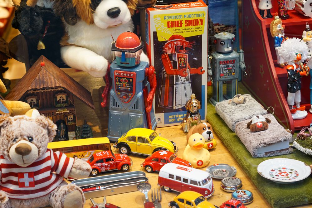 An assortment of vintage tin robots, die-cast cars, and boxed toys